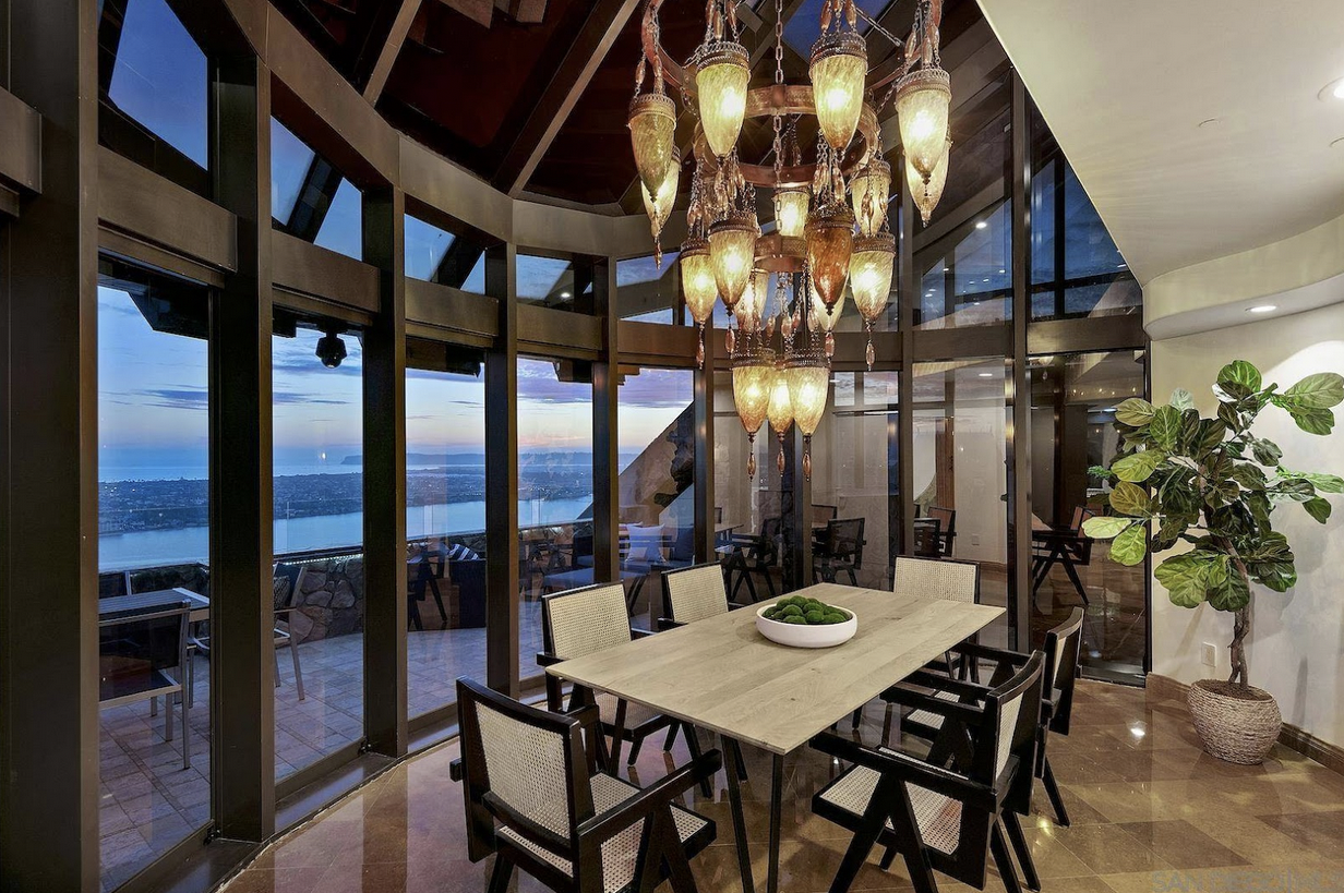 Luxury dining room with shiny stone tile floor, chandelier, floor-to-ceiling windows, and plant